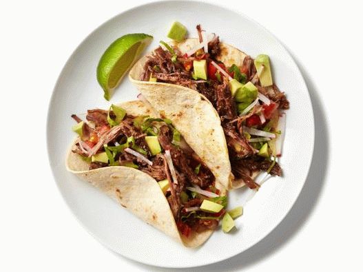“在慢炖锅中用绿色莎莎炖玉米饼的照片牛肉”
