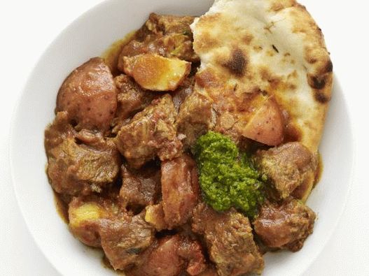 “用咖喱和土豆在慢炖锅中炖牛肉的照片”